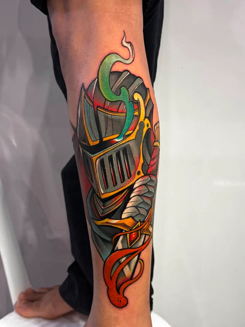 Tatuagem colorida de elmo e armadura na perna