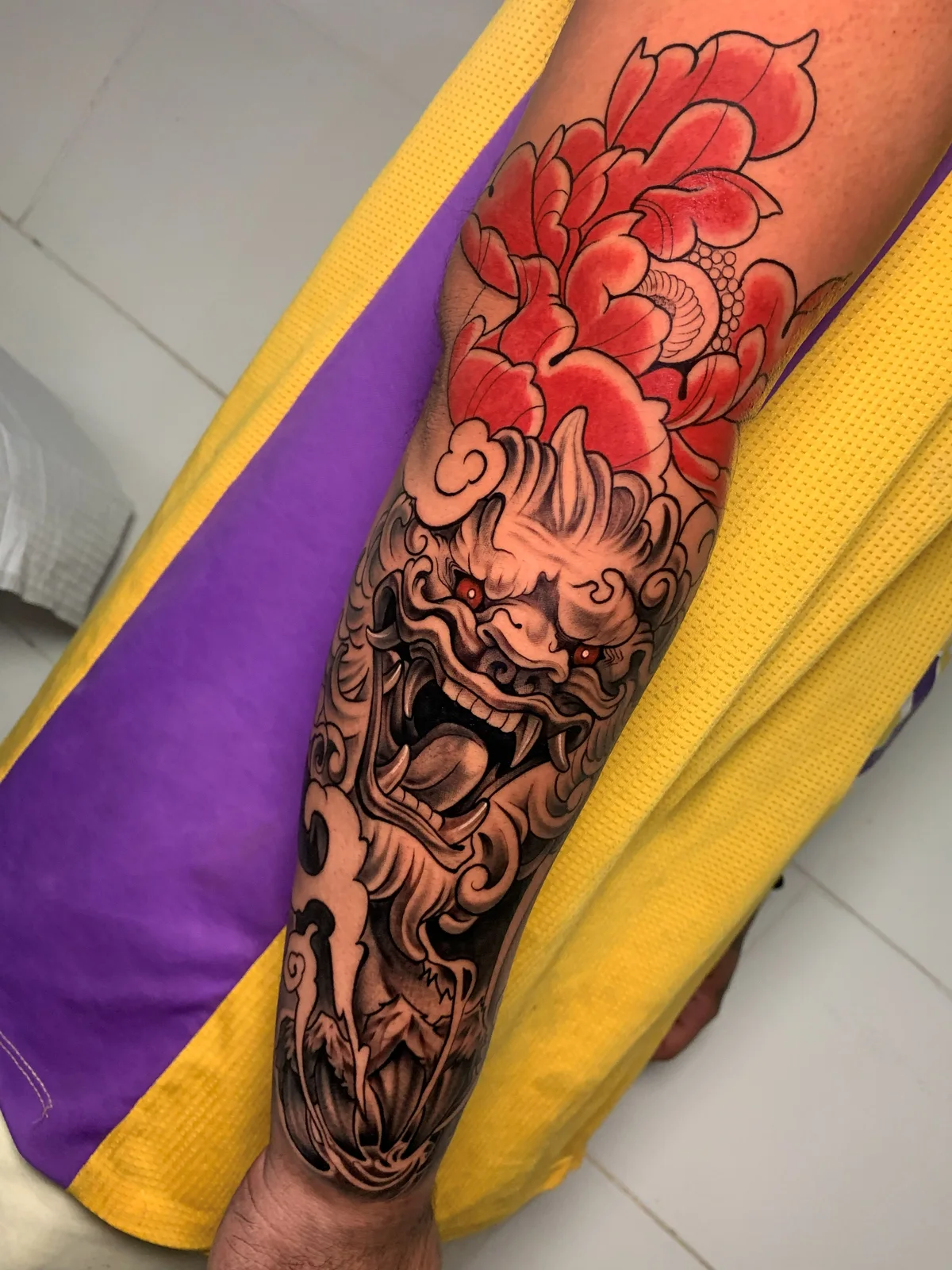 Colorful oriental lion tattoo with a red peony on the leg